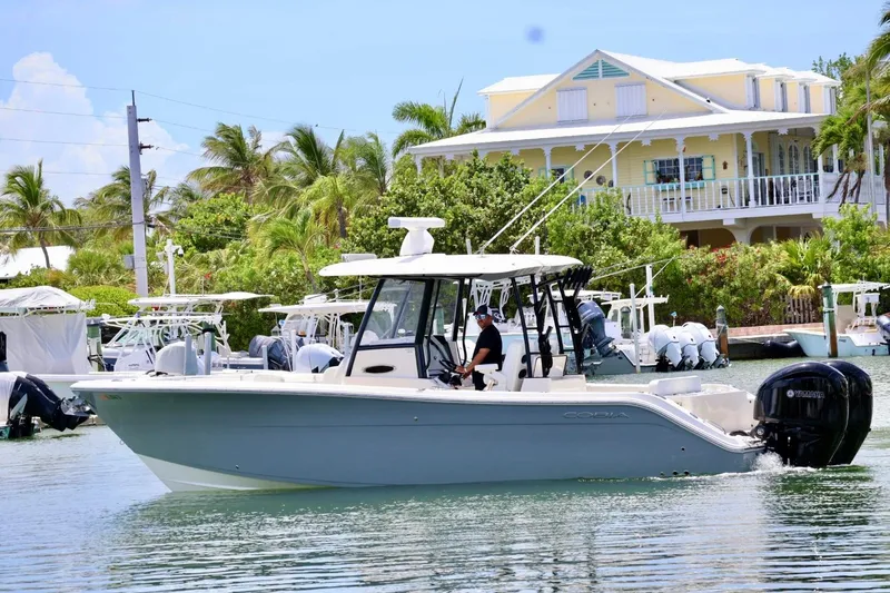 Slide: The Image of 2022 Cobia 301 Center Console boat cruising near a tropical waterfront home. - 3