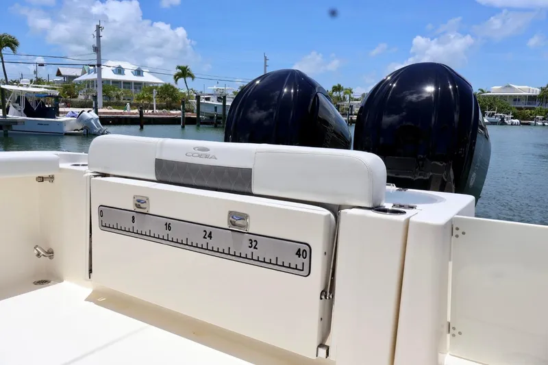 Slide: The Image of 2022 Cobia 301 Center Console boat with dual engines, docked in a sunny marina. - 6