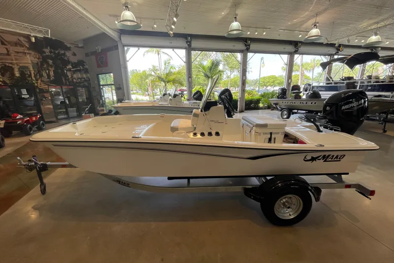 Slide: The Image of 2026 Mako Pro Skiff 15 CC boat displayed in a showroom with modern interior. - 1