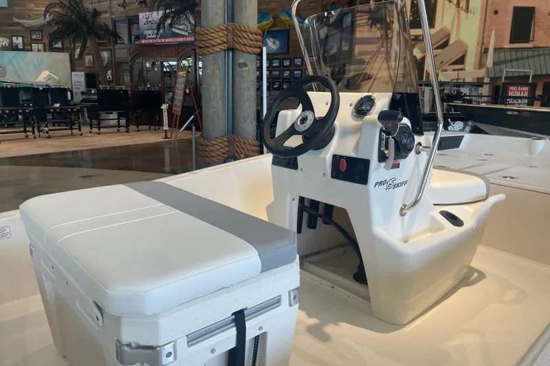 Slide: The Image of 2026 Mako Pro Skiff 15 CC boat interior with steering console in showroom. - 3