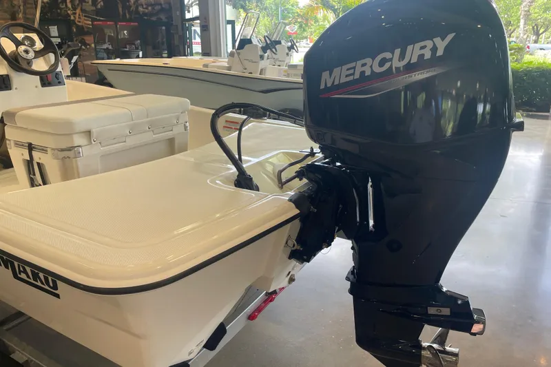 Slide: The Image of 2026 Mako Pro Skiff 15 CC with Mercury outboard motor in showroom setting. - 2
