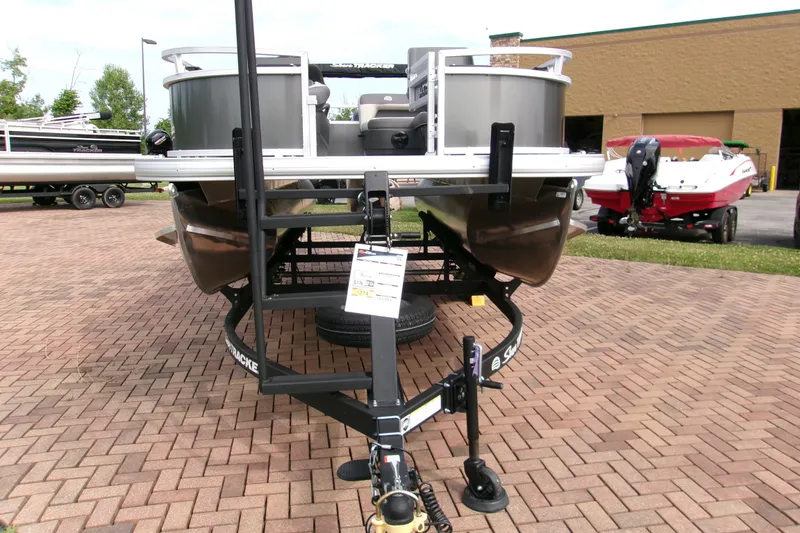 Slide: The Image of 2026 Sun Tracker Bass Buggy 16 XL Select pontoon boat on a trailer, parked on brick pavement. - 3