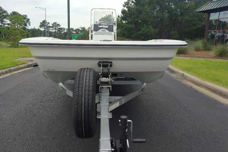 Slide: The Image of 2026 Mako Pro Skiff 17 CC on trailer, parked on asphalt road with greenery. - 6