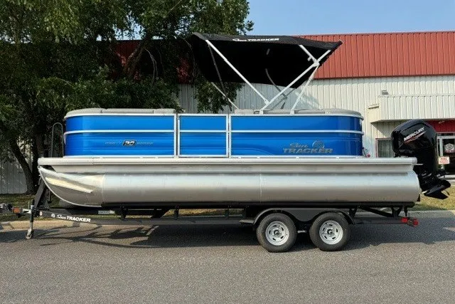 Slide: The Image of 2026 Sun Tracker Party Barge 20 DLX pontoon boat on trailer, blue and silver design. - 1