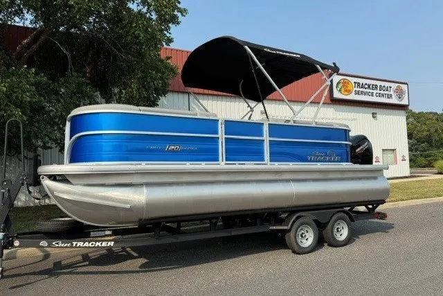 Slide: The Image of 2026 Sun Tracker Party Barge 20 DLX pontoon boat on trailer, parked outside service center. - 4