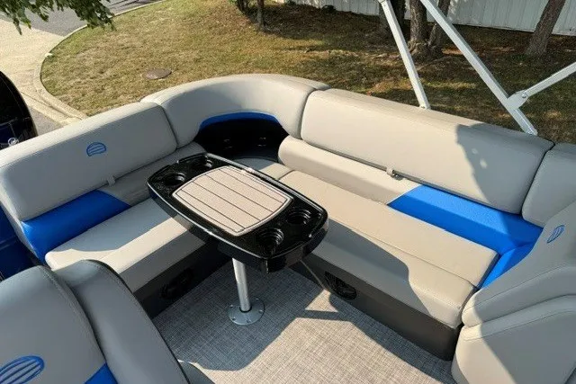 Slide: The Image of 2026 Sun Tracker Party Barge 20 DLX interior with seating and table, outdoor setting. - 8