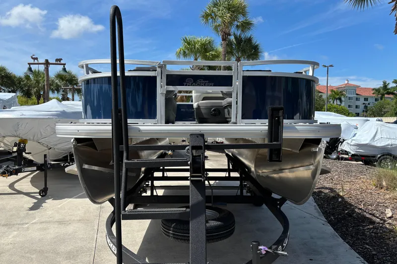 Slide: The Image of 2026 Sun Tracker Bass Buggy 16 XL Select pontoon boat on trailer, parked outdoors. - 72