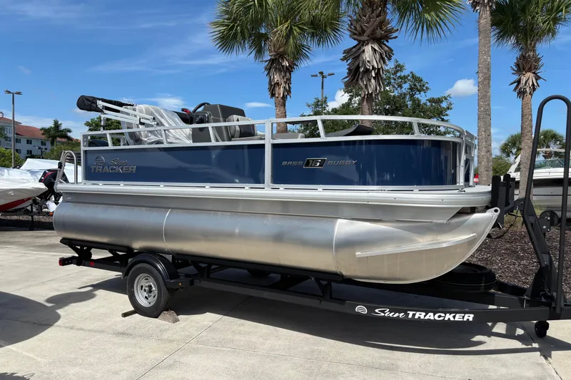 Slide: The Image of 2026 Sun Tracker Bass Buggy 16 XL Select pontoon boat on trailer, parked outdoors. - 71