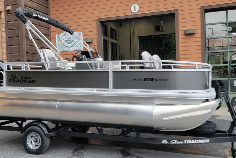 The Image of 2026 Sun Tracker Bass Buggy 18 DLX pontoon boat on trailer outside service entrance. - 0
