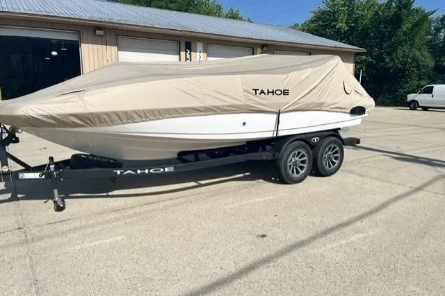 Slide: The Image of 2026 Tahoe 2150 boat covered on trailer, parked outdoors near a building. - 10