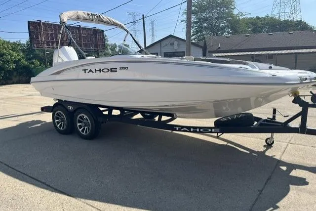 Slide: The Image of 2026 Tahoe 2150 boat on trailer, parked outdoors in a sunny setting. - 2
