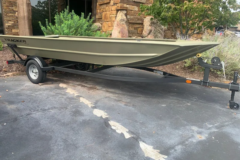 The Image of 2026 Tracker Grizzly 1754 Utility boat on trailer, parked outdoors near stone building. - 0