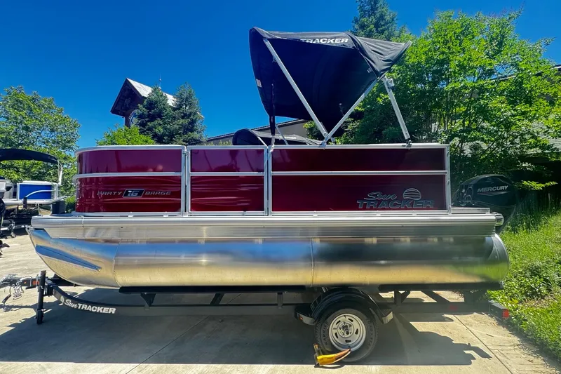 The Image of 2026 Sun Tracker Party Barge 16 DLX pontoon boat with canopy, parked outdoors. - 0