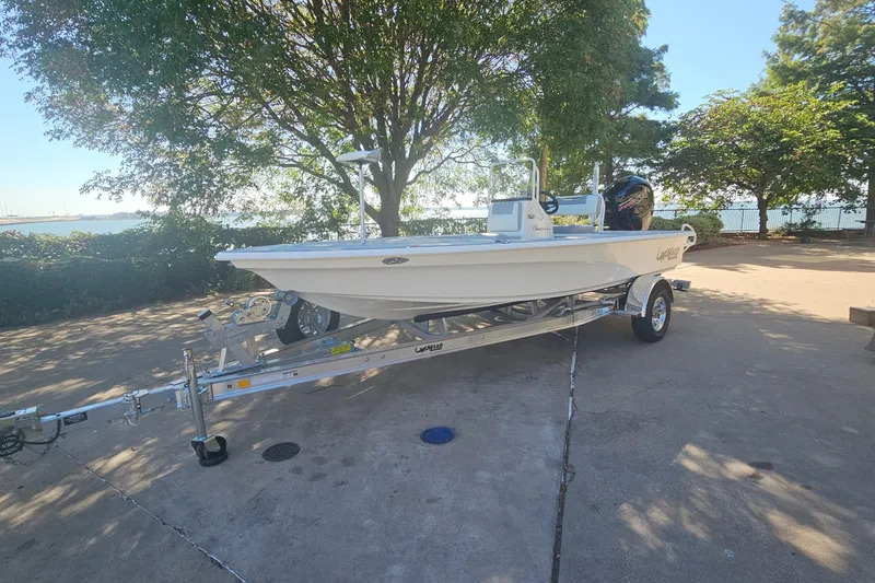 Slide: The Image of 2026 Mako 18 Pro Skiff boat on trailer, parked near a scenic waterfront. - 1