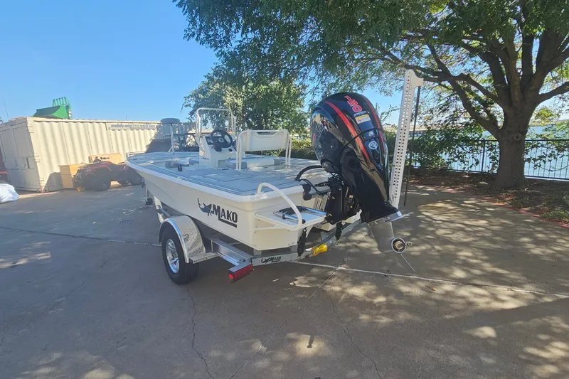 Slide: The Image of 2026 Mako 18 Pro Skiff boat on trailer, parked outdoors under a tree. - 6