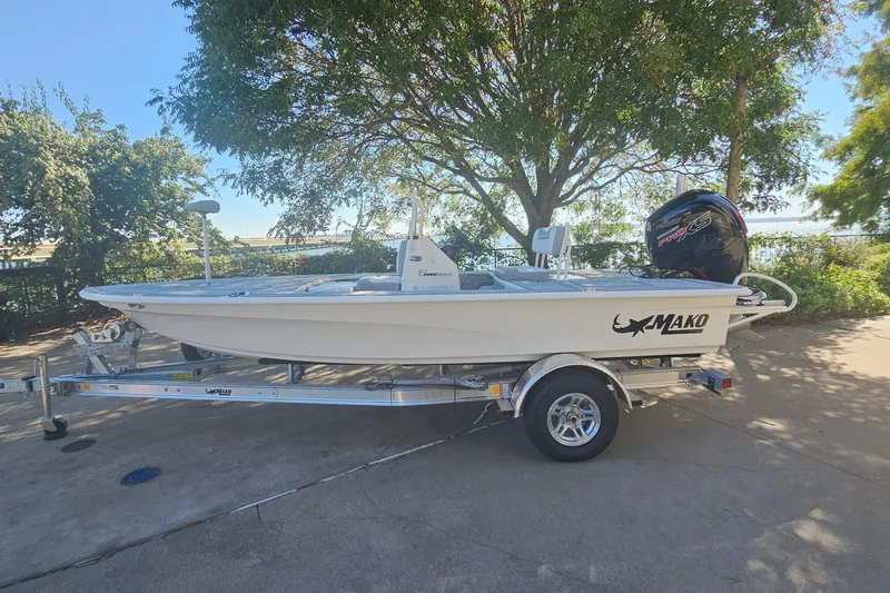 The Image of 2026 Mako 18 Pro Skiff boat on trailer, parked outdoors under a tree. - 0