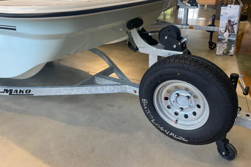 Slide: The Image of 2026 Mako Pro Skiff 15 CC boat on trailer, showcasing tire and hull details. - 5
