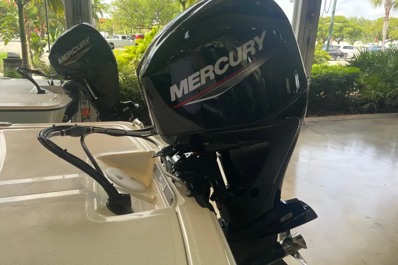 Slide: The Image of 2026 Mako Pro Skiff 15 CC with Mercury outboard motor in a showroom setting. - 2