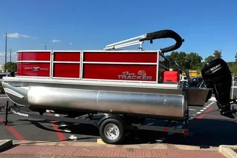 Slide: The Image of 2026 Sun Tracker Party Barge 16 DLX pontoon boat on trailer, red exterior, parked outdoors. - 3