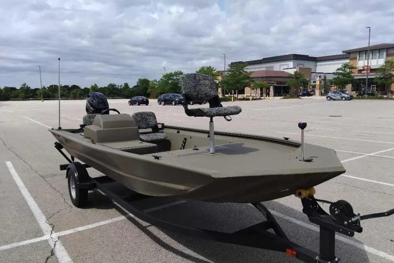 Slide: The Image of 2026 Tracker Grizzly 1754 SC boat on trailer in parking lot, under cloudy sky. - 2