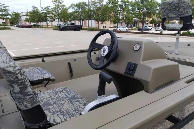 Slide: The Image of 2026 Tracker Grizzly 1754 SC boat interior with camo seats and steering console. - 3