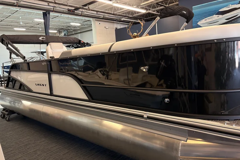 The Image of 2026 Crest Conquest 250 SLSC pontoon boat in showroom, sleek black and white design. - 1