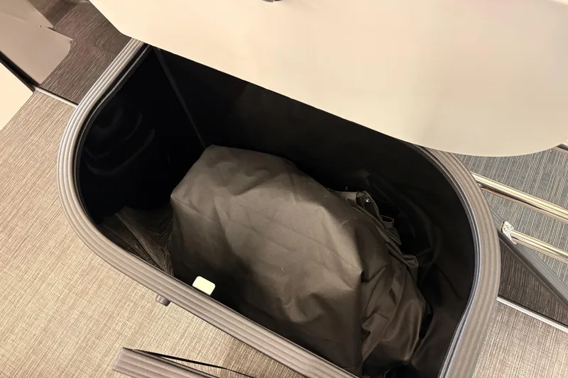 Slide: The Image of Storage compartment in 2026 Crest Conquest 250 SLSC boat, featuring a black bag inside. - 16