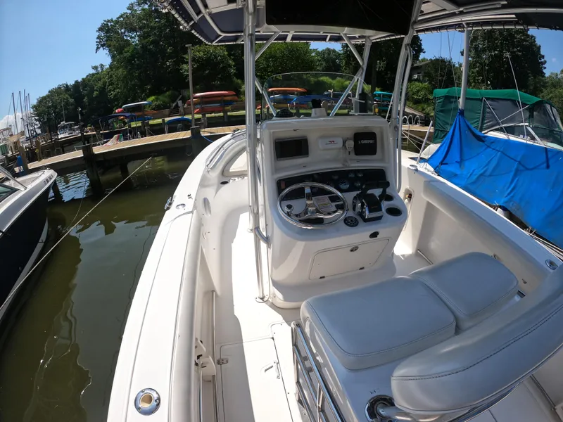 Slide: The Image of 2004 Boston Whaler 270 Outrage boat interior at dock, featuring helm and seating area. - 5