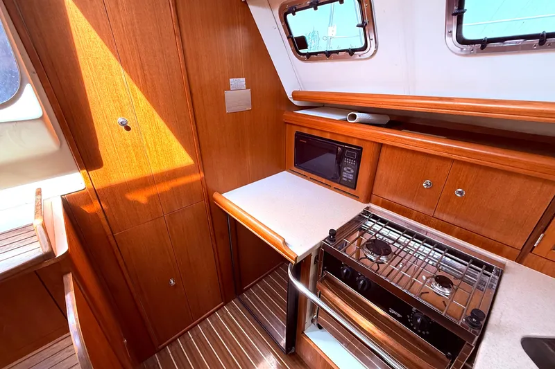 Slide: The Image of 2005 Hunter 41 Deck Salon kitchen with wood cabinetry, stove, and microwave. - 33