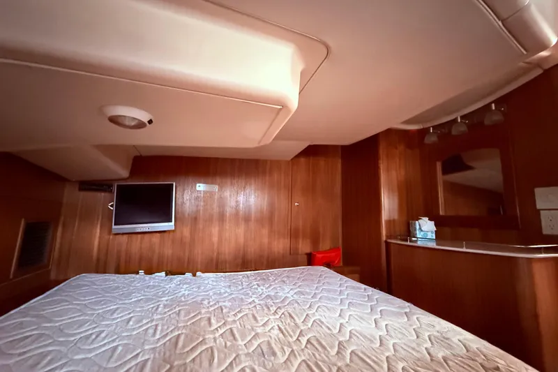 Slide: The Image of Interior of 2005 Hunter 41 Deck Salon with bed, TV, and wooden paneling. - 49