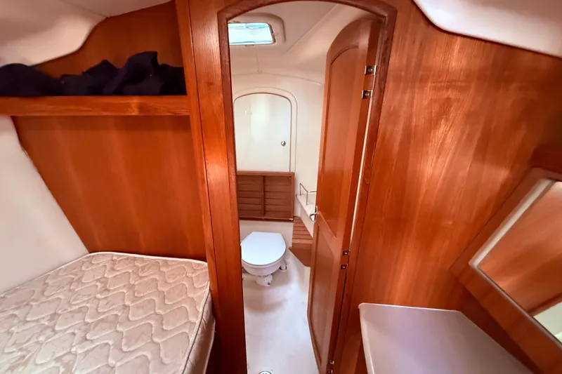 Slide: The Image of Interior of 2005 Hunter 41 Deck Salon, featuring wooden cabinetry and a compact bathroom. - 57