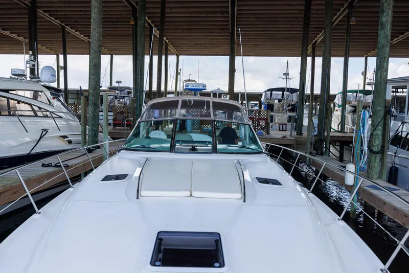 Slide: The Image of 2002 Sea Ray 410 Express Cruiser docked in a marina under a wooden canopy. - 18