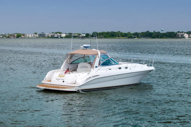 Slide: The Image of 2002 Sea Ray 410 Express Cruiser on calm water, distant shoreline view. - 2