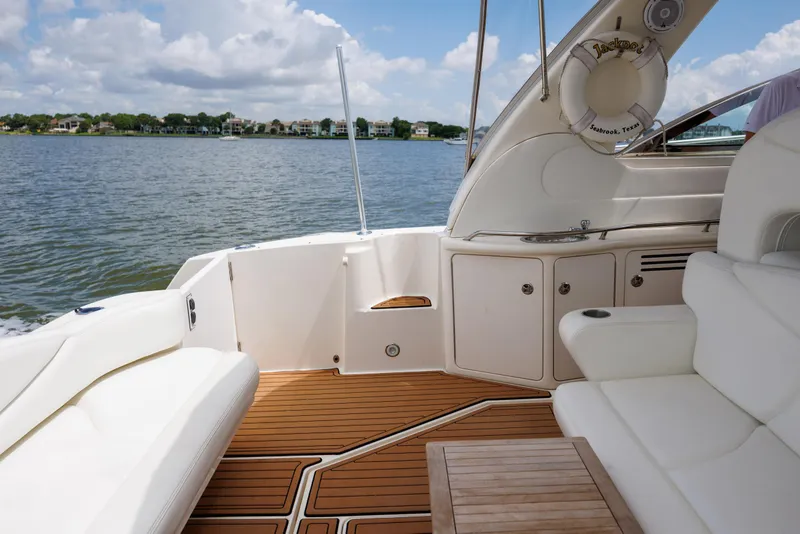 Slide: The Image of 2002 Sea Ray 410 Express Cruiser interior with white seating and wooden deck, overlooking calm waters. - 25