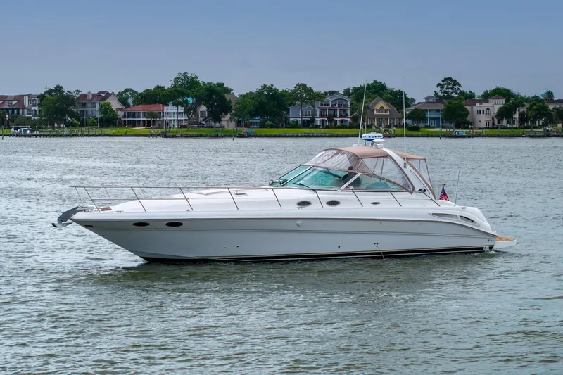 Slide: The Image of 2002 Sea Ray 410 Express Cruiser on calm water near residential shoreline. - 34