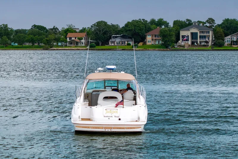 Slide: The Image of 2002 Sea Ray 410 Express Cruiser on a serene lake with waterfront homes. - 35