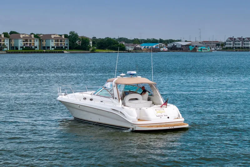 Slide: The Image of 2002 Sea Ray 410 Express Cruiser on calm waters near residential shoreline. - 36
