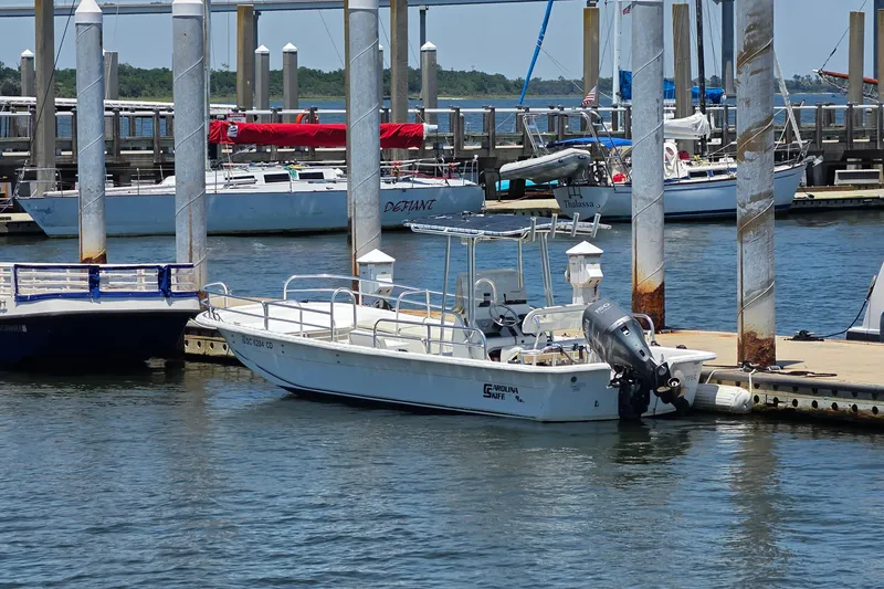 The Image of 2011 Carolina Skiff 258 DLV boat docked at a marina with other vessels. - 1