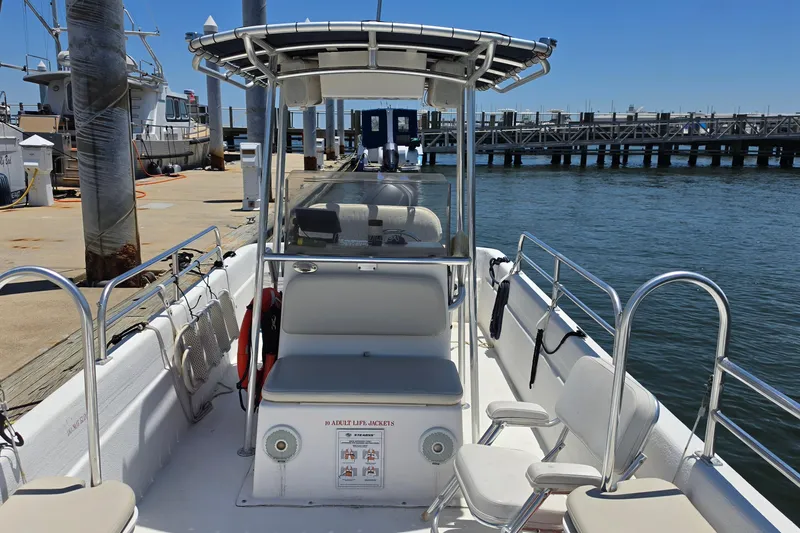 Slide: The Image of 2011 Carolina Skiff 258 DLV boat docked at marina, featuring seating and safety equipment. - 11