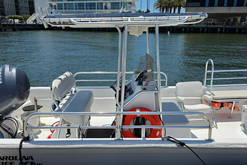 Slide: The Image of 2011 Carolina Skiff 258 DLV boat docked, featuring seating and safety equipment. - 3