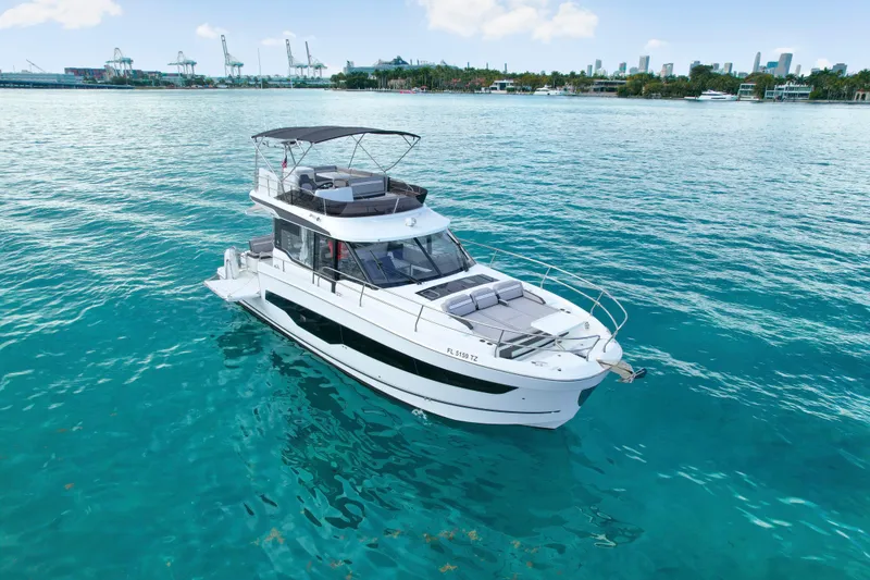 Slide: The Image of 2025 Jeanneau NC 1295 Fly yacht on clear blue water, city skyline in background. - 4