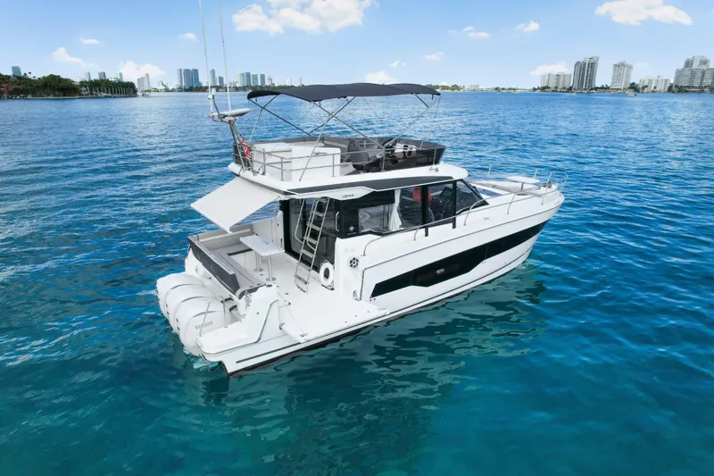 Slide: The Image of 2025 Jeanneau NC 1295 Fly yacht on clear blue water with city skyline. - 5