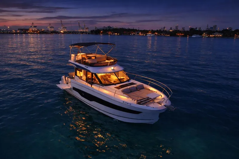 Slide: The Image of 2025 Jeanneau NC 1295 Fly yacht illuminated at sunset on calm waters. - 6