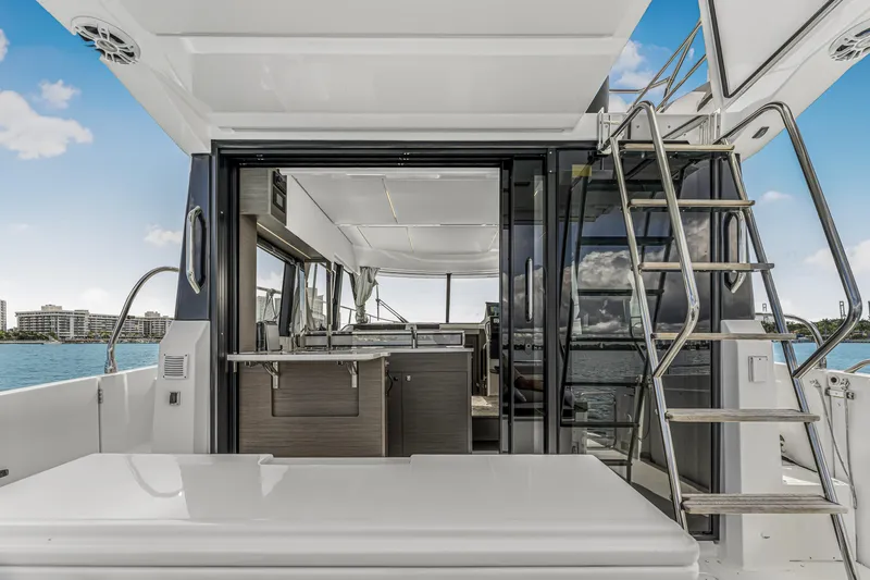 Slide: The Image of 2025 Jeanneau NC 1295 Fly yacht interior with open sliding doors and staircase, ocean view. - 7