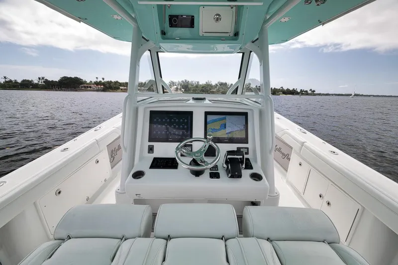 Slide: The Image of 2017 Yellowfin 39 Offshore boat cockpit with dual screens and steering wheel on calm water. - 12