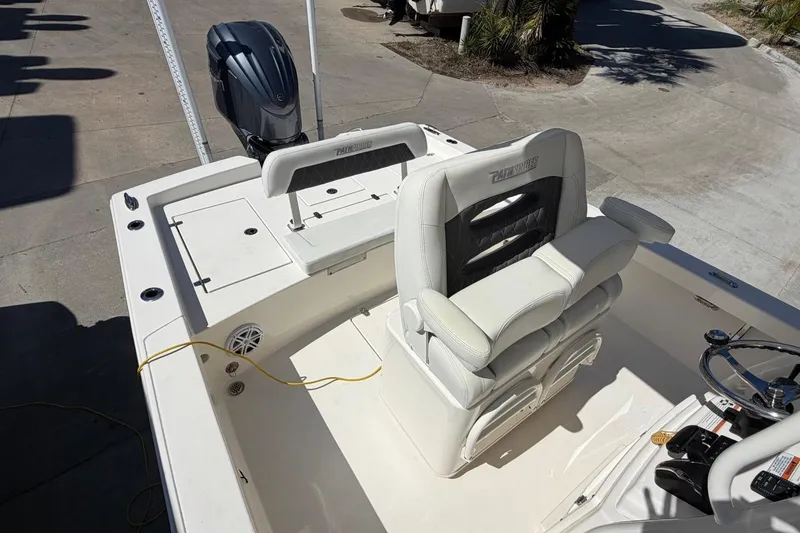 Slide: The Image of 2022 Pathfinder 2600 HPS boat interior with seating and steering wheel, docked outdoors. - 16