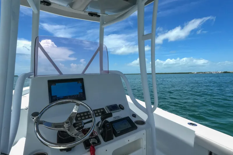 Slide: The Image of 2019 Blue Wave 2800 Pure Hybrid boat dashboard with steering wheel, GPS, and ocean view. - 11