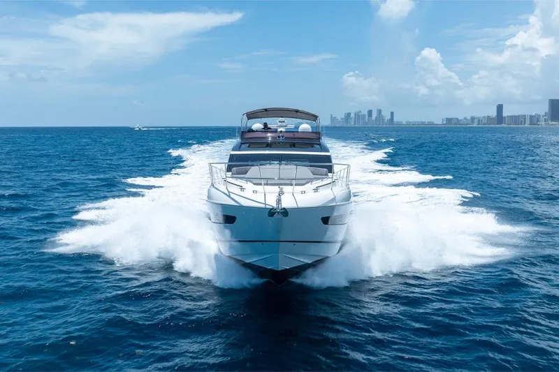 Slide: The Image of 2023 Princess S66 Sportbridge yacht cruising on open ocean with city skyline in background. - 39