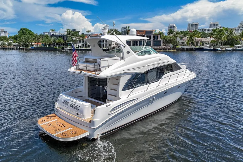 Slide: The Image of 2001 Sea Ray 540 Cockpit Motor Yacht cruising on a sunny day, waterfront homes in background. - 9