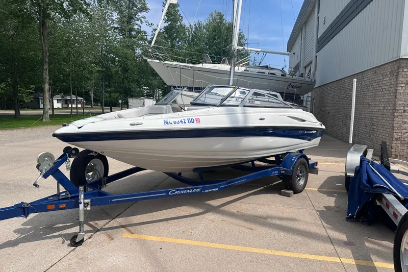 Slide: The Image of 2015 Crownline 21 SS boat on trailer, parked outdoors near a building. - 0